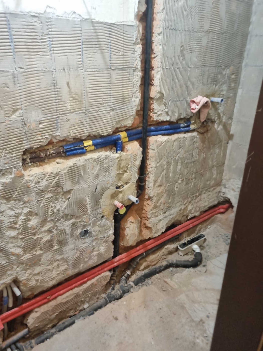 Geöffnete Badezimmerwand mit neu verlegten Wasser- und Abflussleitungen während der Sanierung