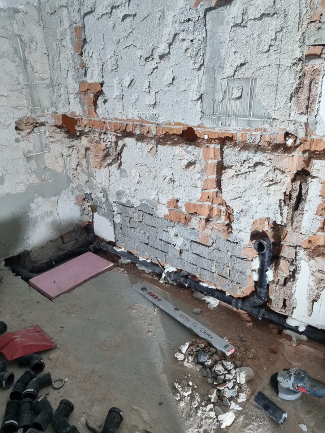 Freigelegte Badezimmerwand und Boden mit erneuerten Abflussleitungen während der Sanierung