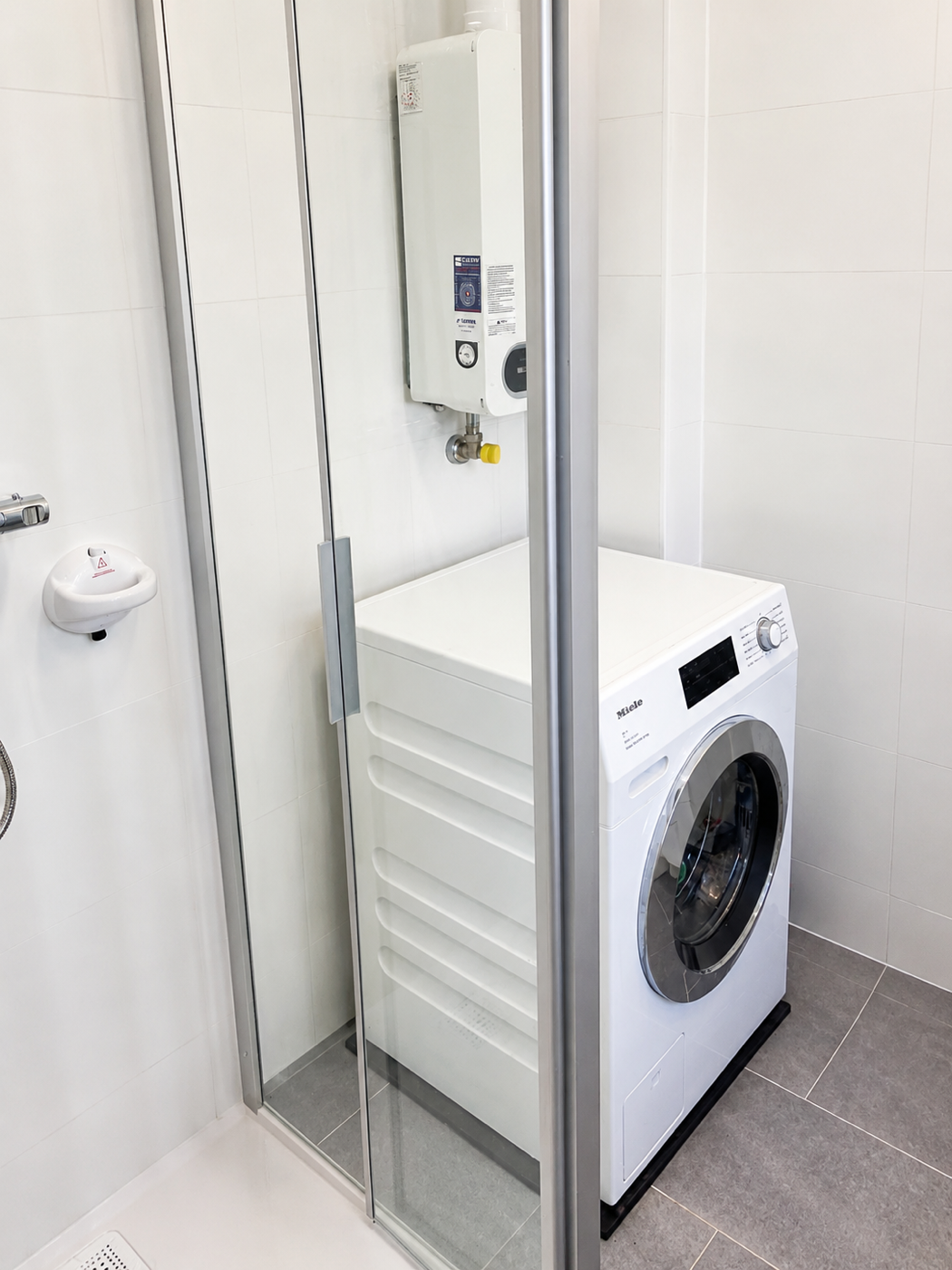 Neu organisiertes helles Bad mit Dusche, Waschmaschine und weiterhin zugänglicher Therme